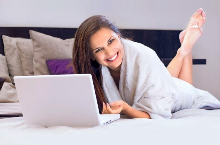 a woman lying on a bed with a laptop