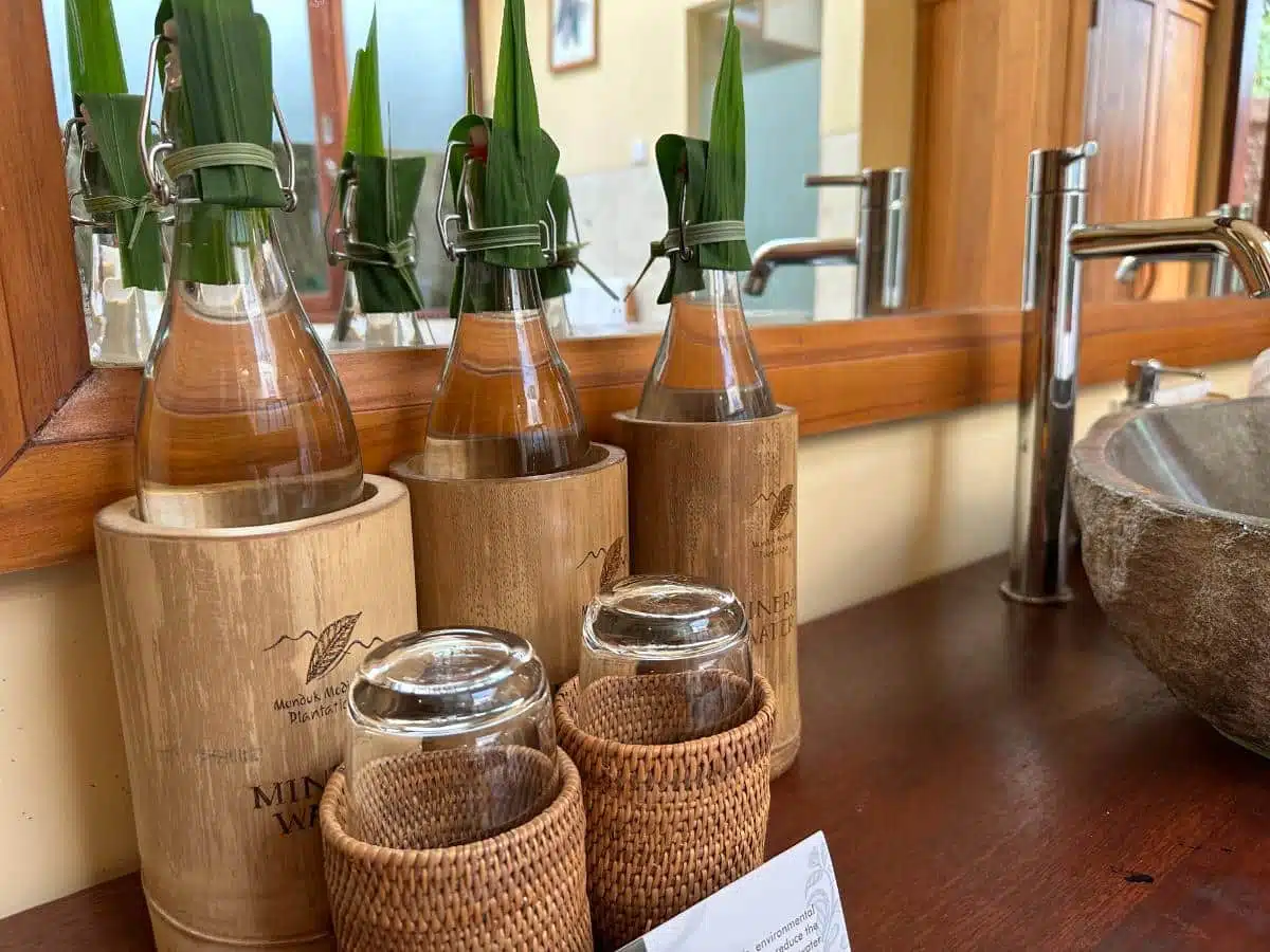 Eco-Friendly Branded Glass Water Bottles In Bamboo Holders On The Bathroom Vanity At Munduk Moding Plantation, Bali