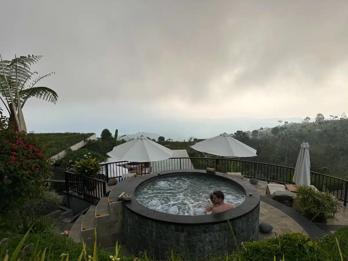 Lower Infinity Pool Surrounded By Tropical Plants With Hillside Villas In The Background At Munduk Moding Plantation, Bali