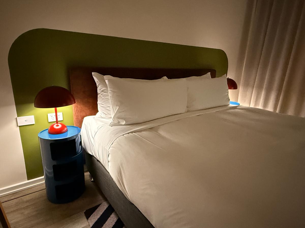 a bed with white sheets and a red lamp