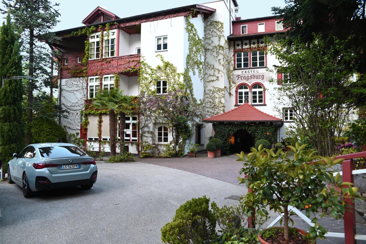 Ivy-Covered Bavarian-Style Exterior Of Castel Fragsburg Relais &Amp; Châteaux Hotel With Red Shutters And Entrance In Merano, South Tyrol, Italy
