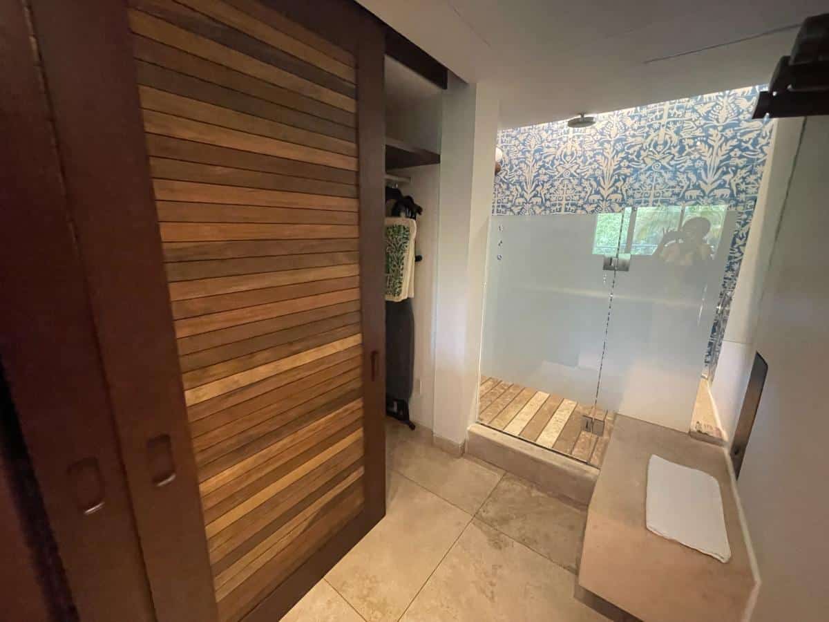 Open-Concept Bathroom With Walk-In Shower, Decorative Blue Tile, And Sliding Wooden Barn Door In A Suite At Xcaret Arte Resort Mexico