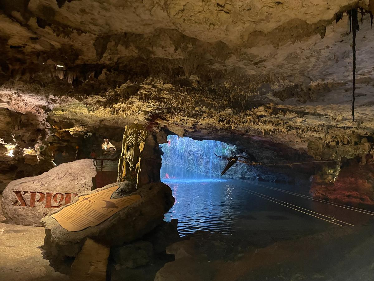 Underground Cenote Cave At Xplor Adventure Park Near Xcaret Arte With Stalactites, Turquoise Water, And The Xplor Sign